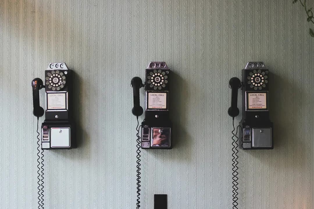 Three vintage wall-mounted telephones side by side