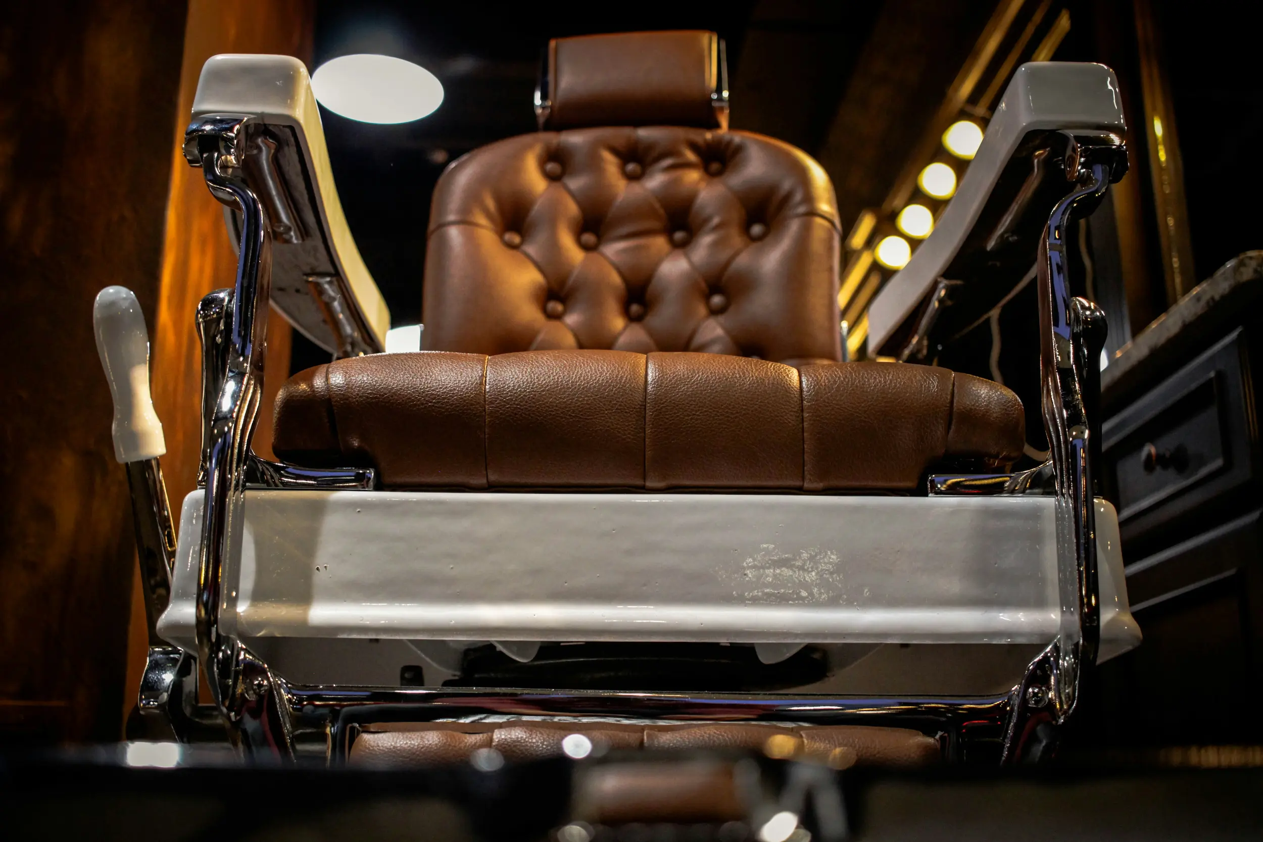 A brown leather barber chair with polished chrome fittings